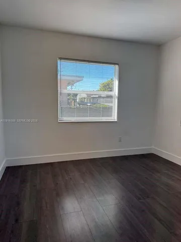 an empty room with wooden floor and a window