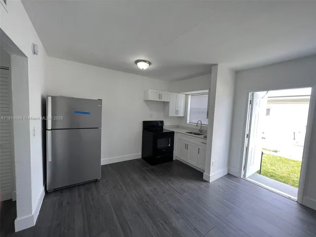 a kitchen with a refrigerator a stove top oven and wooden floor
