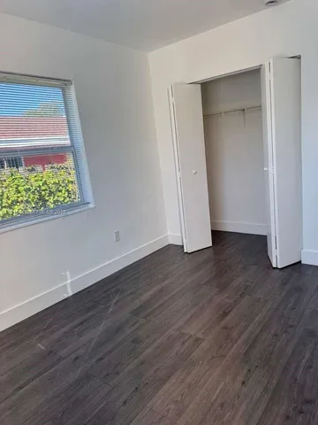 an empty room with wooden floor and window