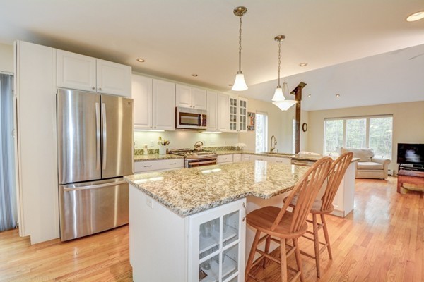 149 Nourse Road Bolton, MA 01740 - Photo 11 of 30 a kitchen with stainless steel appliances granite countertop a refrigerator a stove a sink a dining table and chairs with wooden floor