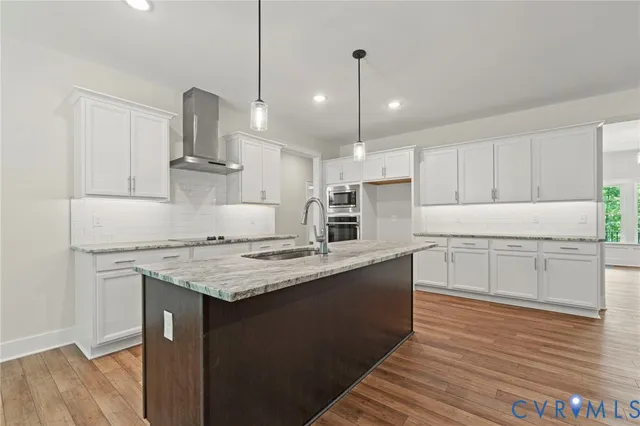 a kitchen with stainless steel appliances kitchen island granite countertop a table chairs in it and white cabinets