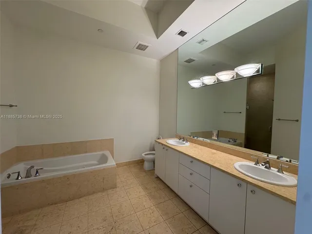 a bathroom with a tub a double vanity sink and mirror