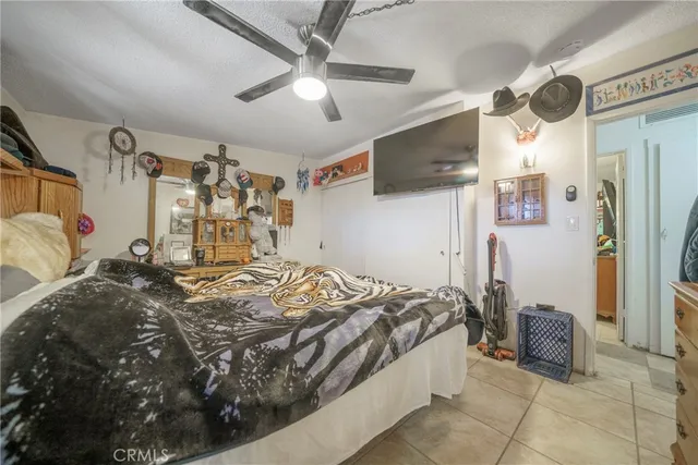 a bedroom with a bed a flat screen tv and a ceiling fan