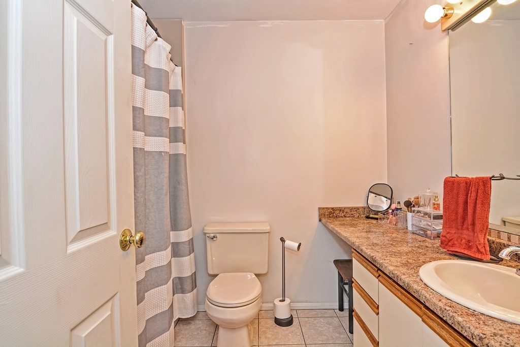 96 Danforth Street, Unit 19 Taunton, MA 02780 - Photo 19 of 31 a bathroom with a granite countertop sink a toilet and a mirror