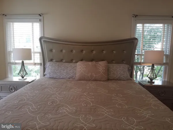 a large white bed in a bedroom next to a window
