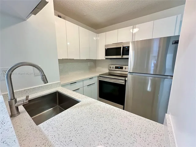 a kitchen with a refrigerator sink and cabinets