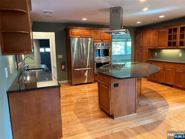 a kitchen with stainless steel appliances granite countertop a sink a stove and a refrigerator