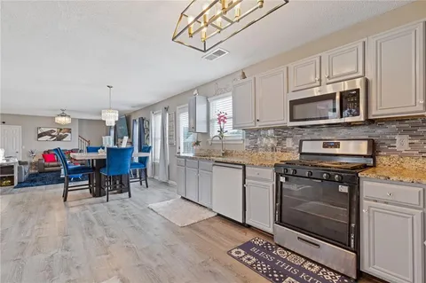 a kitchen with granite countertop a stove a sink and a microwave