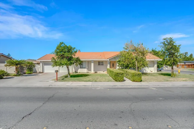 a view of a house with a yard and palm trees