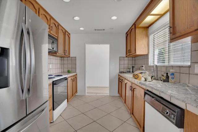 a kitchen with stainless steel appliances granite countertop a refrigerator a stove and a sink