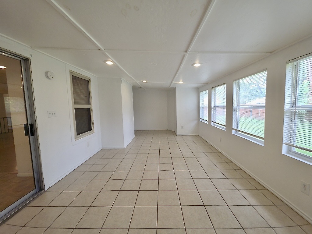 4901 Wing Road Austin, TX 78749 - Photo 10 of 28 Spacious sunroom featuring tile flooring, multiple windows providing natural light, recessed ceiling lighting, and a sliding glass door