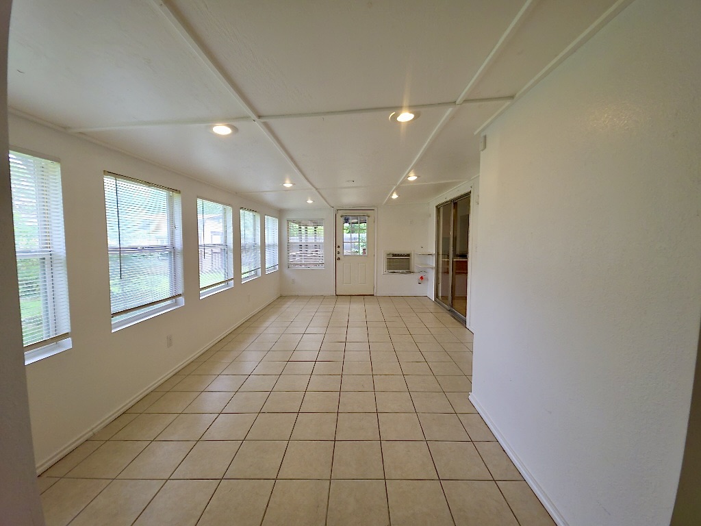 4901 Wing Road Austin, TX 78749 - Photo 11 of 28 Bright sunroom featuring a series of windows, tiled flooring, recessed lighting, a white paneled ceiling, and a rear exit door