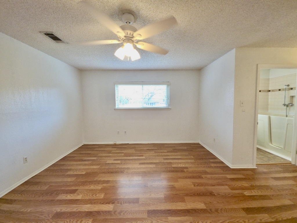 4901 Wing Road Austin, TX 78749 - Photo 12 of 28 Spacious interior featuring wood-finish flooring, white walls, and a ceiling fan with integrated lighting