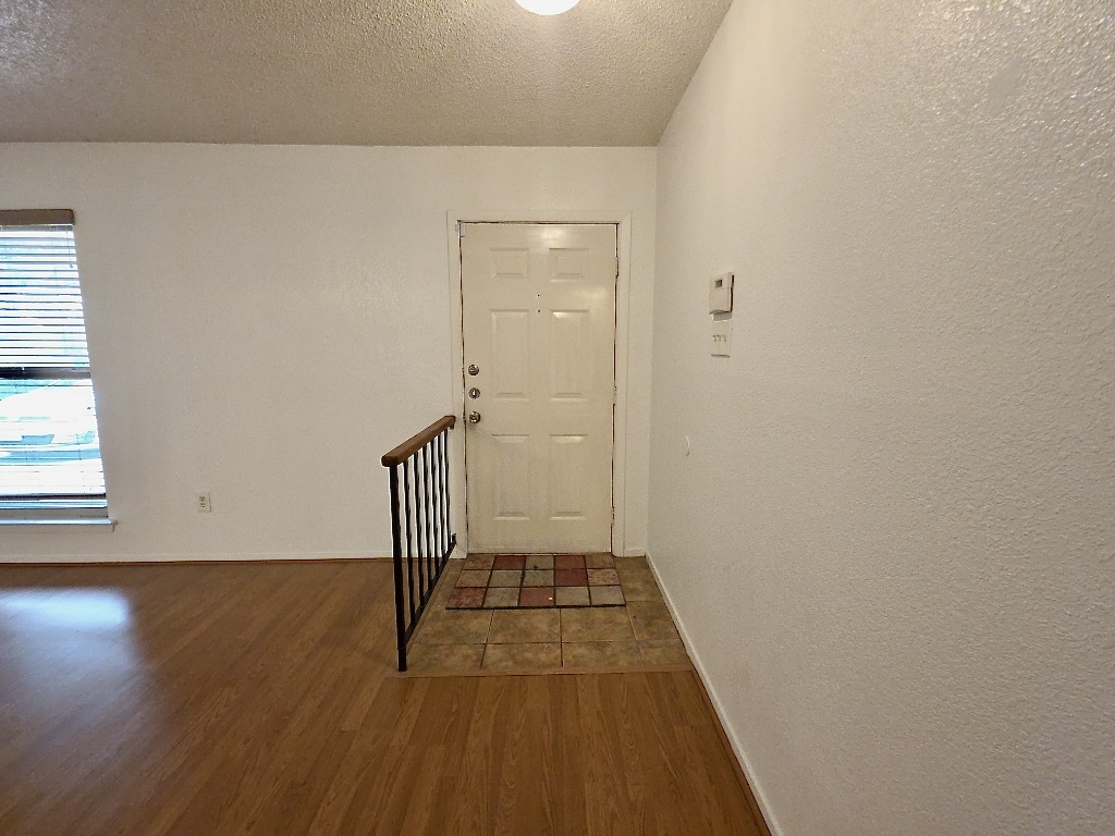 4901 Wing Road Austin, TX 78749 - Photo 2 of 28 Entryway featuring a white paneled door, tile flooring, and wood-finish flooring extending into the main area