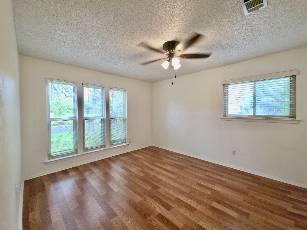 4901 Wing Road Austin, TX 78749 - Photo 20 of 28 Spacious room featuring wood-finish flooring, multiple windows with blinds, a ceiling fan with integrated lighting, and neutral wall paint