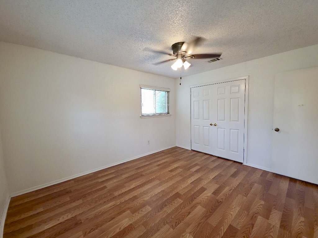 4901 Wing Road Austin, TX 78749 - Photo 21 of 28 Spacious interior room featuring wood-finish flooring, a ceiling fan with integrated lighting, a window with horizontal blinds, and a double-door closet with paneling