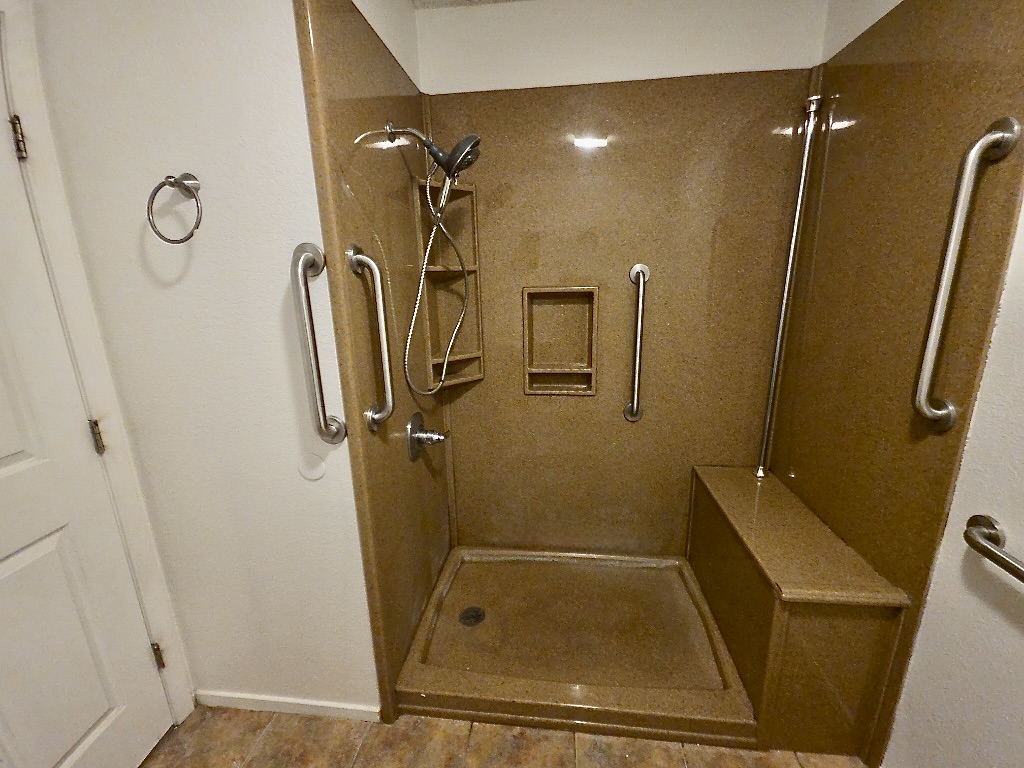 4901 Wing Road Austin, TX 78749 - Photo 22 of 28 Walk-in shower featuring a built-in bench, integrated shelving, and multiple grab bars