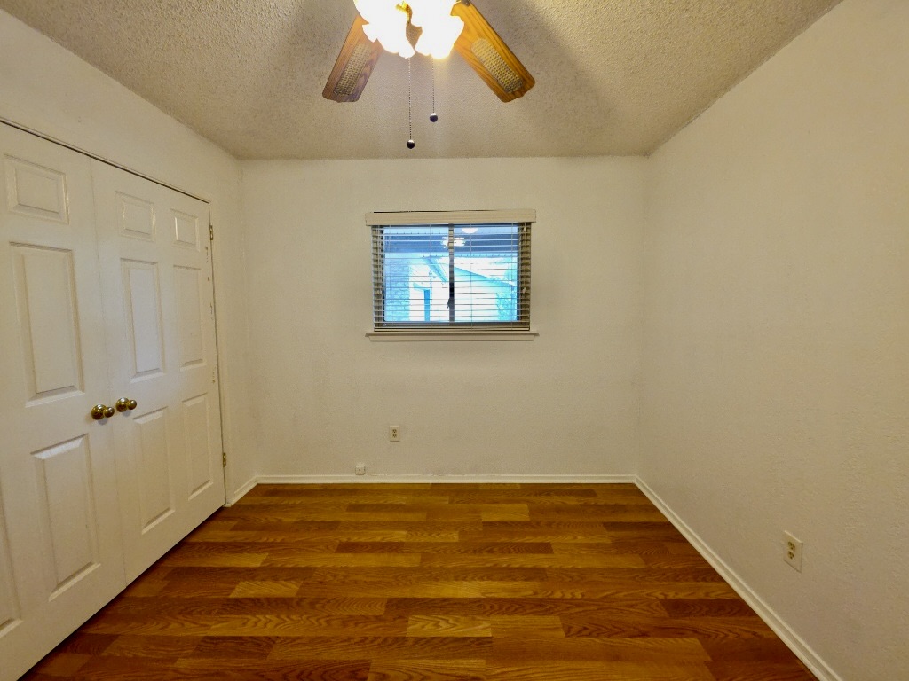 4901 Wing Road Austin, TX 78749 - Photo 24 of 28 Room featuring wood-finish flooring, a double-door closet, and a ceiling fan with integrated lighting