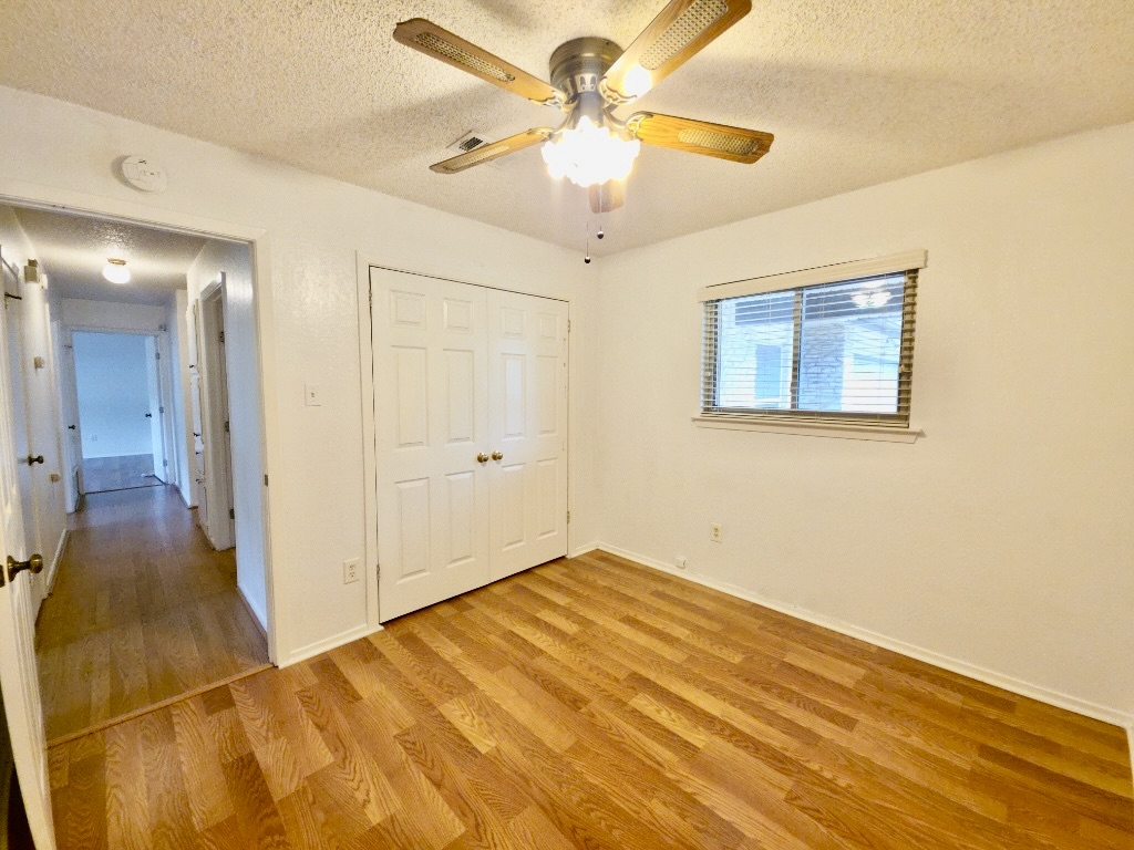 4901 Wing Road Austin, TX 78749 - Photo 25 of 28 Room featuring wood-finish flooring, a double-door closet, and a ceiling fan with integrated lighting