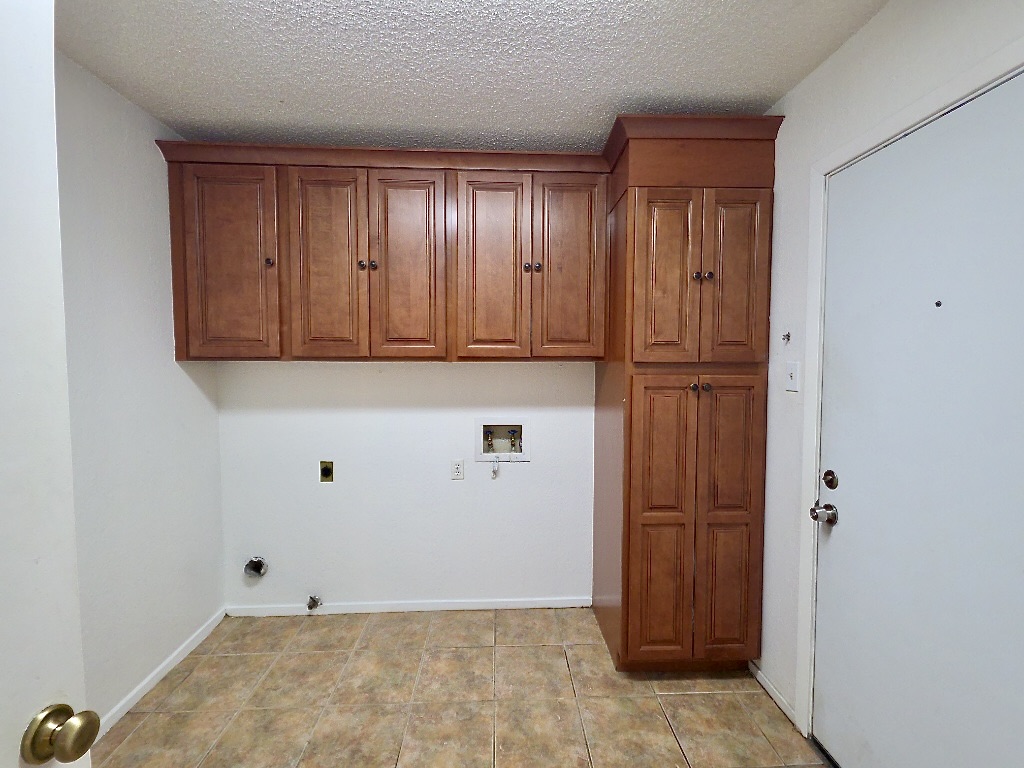 4901 Wing Road Austin, TX 78749 - Photo 26 of 28 Utility space featuring ceramic tile flooring, white walls, and wood cabinetry