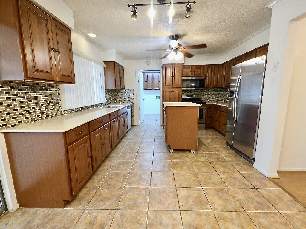 4901 Wing Road Austin, TX 78749 - Photo 5 of 28 Kitchen featuring extensive wood cabinetry, light-toned countertops, and a mosaic tile backsplash