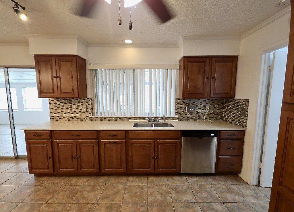 4901 Wing Road Austin, TX 78749 - Photo 6 of 28 Kitchen featuring wood cabinetry, light-toned countertops, a mosaic tile backsplash, and a double basin sink