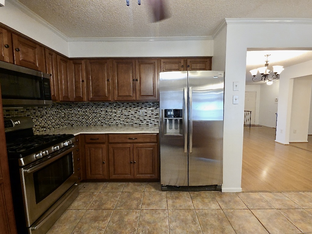 4901 Wing Road Austin, TX 78749 - Photo 8 of 28 Kitchen featuring wood cabinetry, stainless steel appliances, mosaic tile backsplash, and tile flooring
