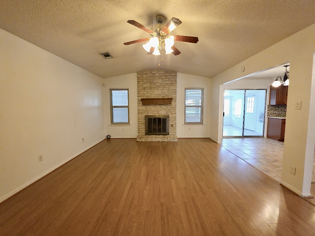 4901 Wing Road Austin, TX 78749 - Photo 9 of 28 Spacious living area featuring wood-finish flooring, a vaulted ceiling, and a ceiling fan with integrated lighting