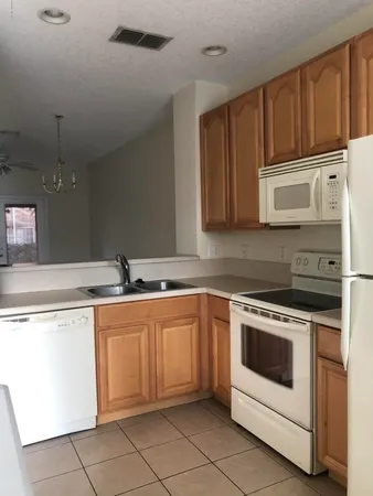 an empty room with chandelier fan and windows