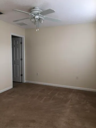 a view of a hallway with wooden floor and a bathroom