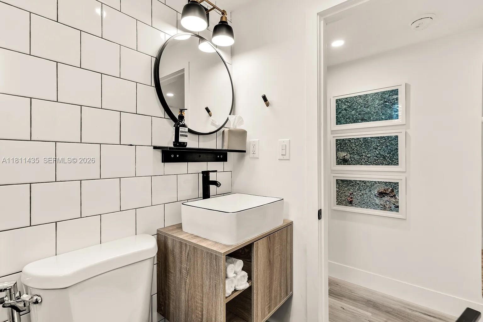 1237 Northwest 33rd Avenue Miami, FL 33125 - Photo 24 of 35 a bathroom with a sink a toilet and a mirror