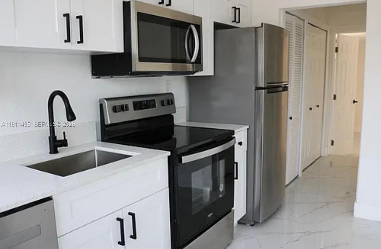 1237 Northwest 33rd Avenue Miami, FL 33125 - Photo 3 of 35 a kitchen with stainless steel appliances granite countertop a refrigerator sink and stove