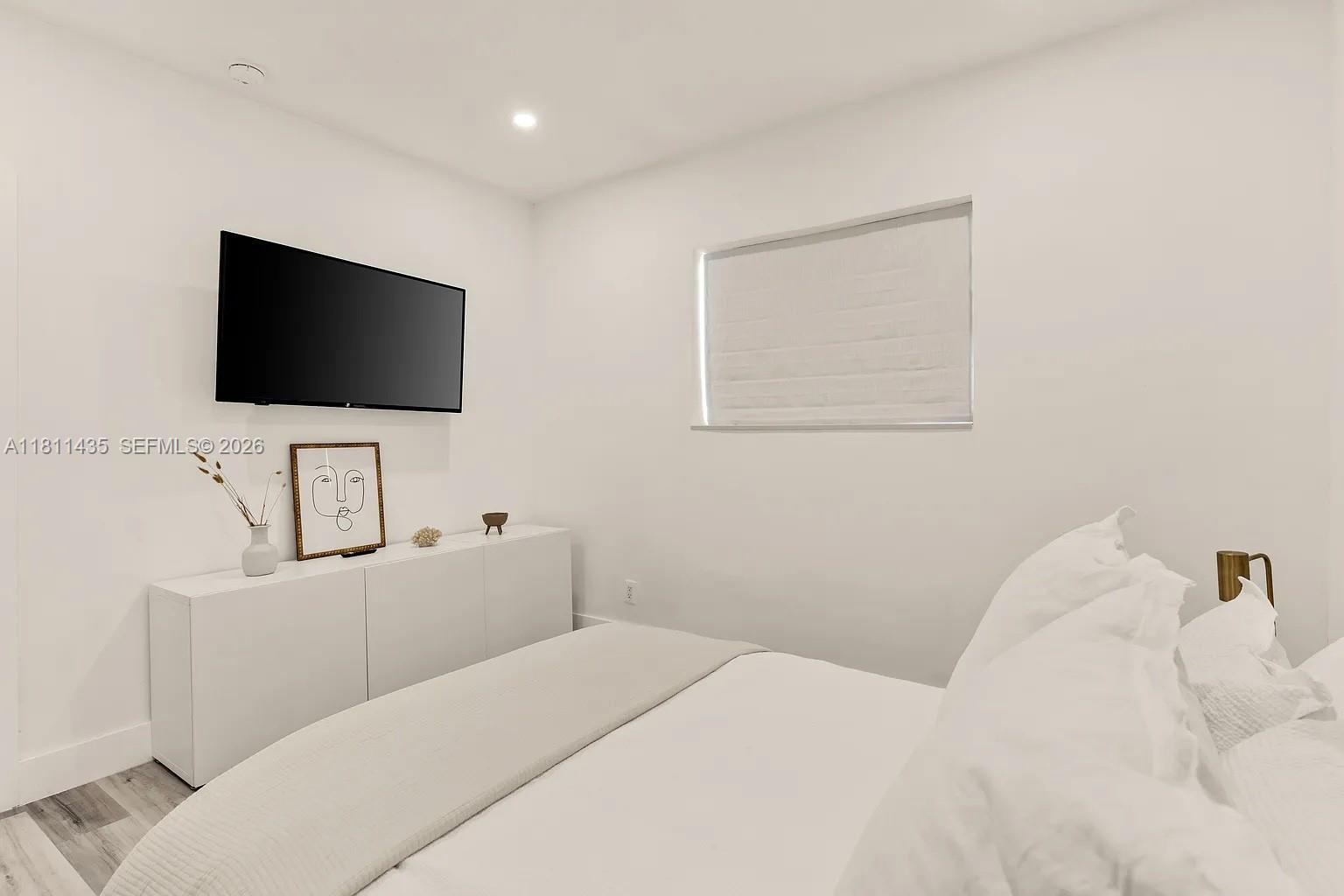 1237 Northwest 33rd Avenue Miami, FL 33125 - Photo 31 of 35 a bedroom with a bed a flat screen tv and a window