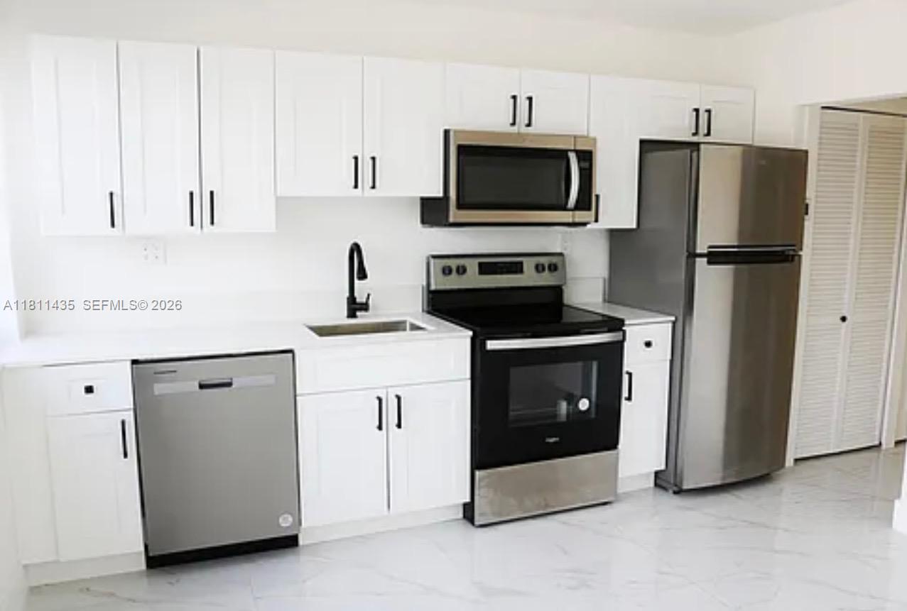 1237 Northwest 33rd Avenue Miami, FL 33125 - Photo 4 of 35 a kitchen with a refrigerator stove and white cabinets