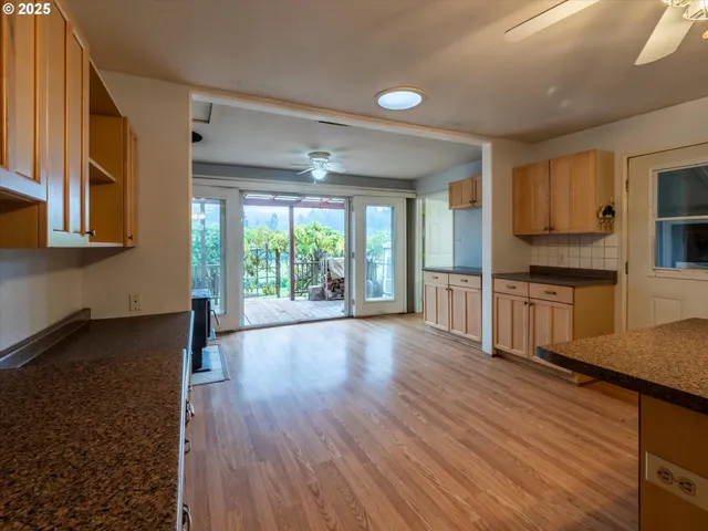 a open kitchen with granite countertop a stove top oven a sink and white cabinets with wooden floor