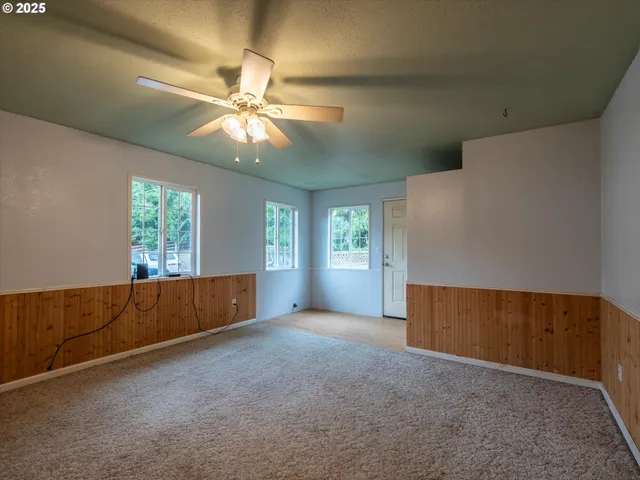 an empty room with windows and fan