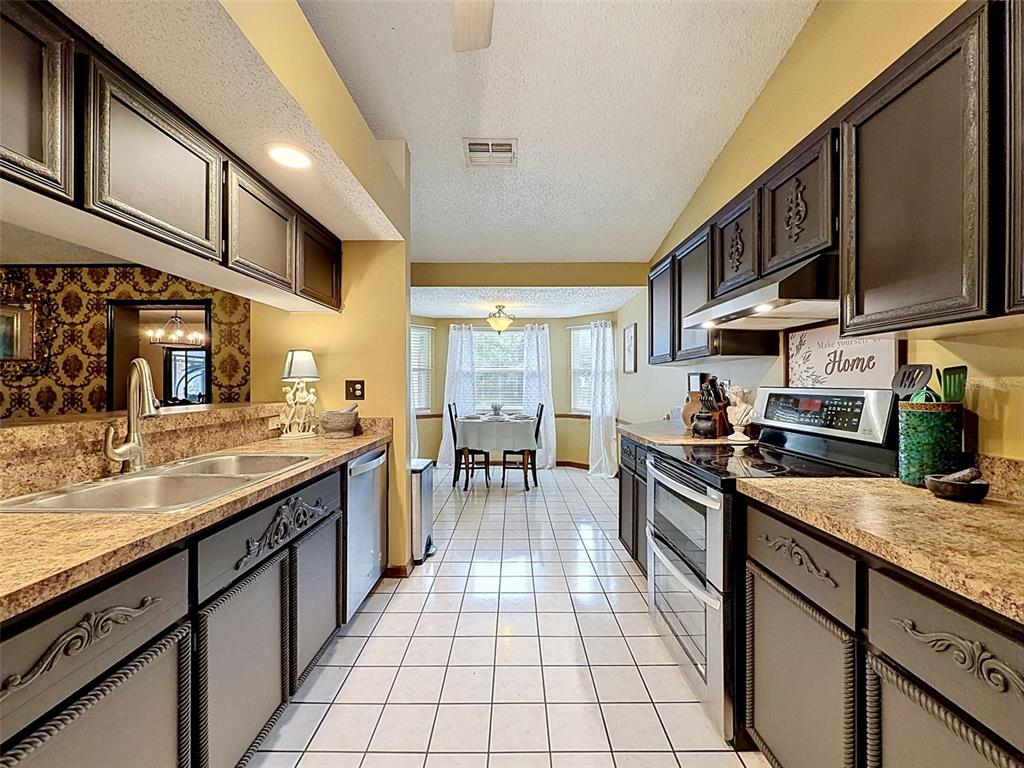 7111 Ricker Avenue Webster, FL 33597 - Photo 15 of 41 a kitchen with stainless steel appliances granite countertop a stove top oven a sink a dining table and chairs with wooden floor