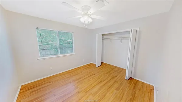 a view of a room with wooden floor and a ceiling fan