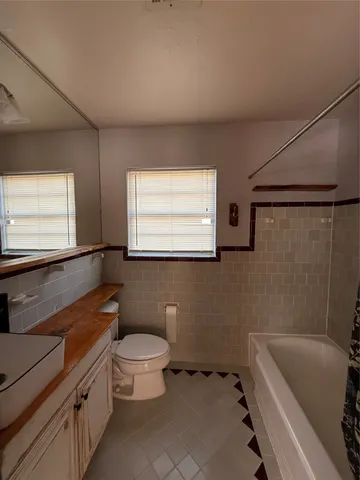 a bathroom with a sink a toilet a window and a bathtub