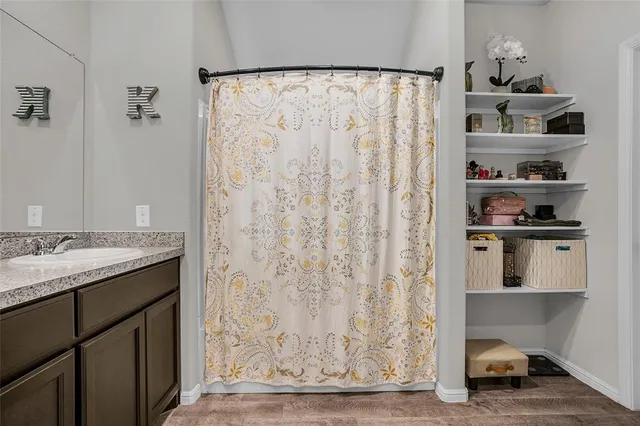 a bathroom with a granite countertop sink and a shower curtain
