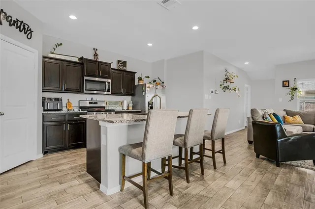 a kitchen with stainless steel appliances kitchen island granite countertop a table and chairs in it