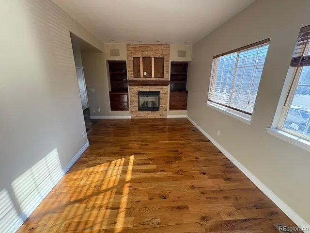 a view of an empty room with wooden floor and windows