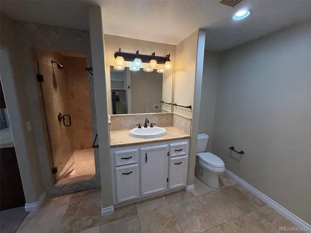 a bathroom with a granite countertop sink toilet and shower