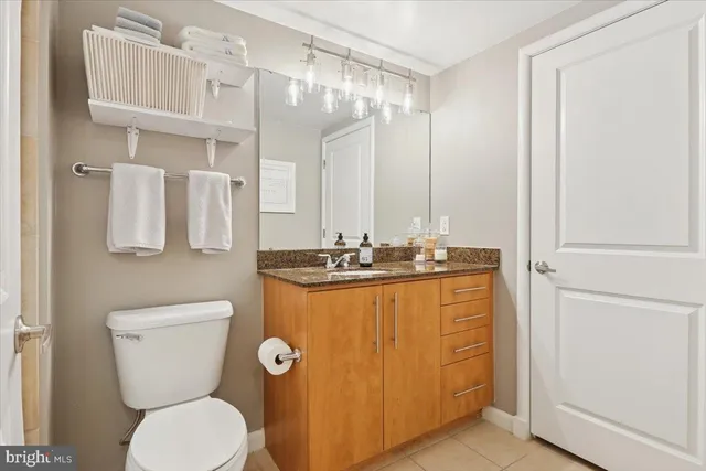 a bathroom with a granite countertop toilet sink and mirror