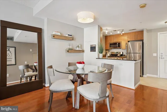 a kitchen with stainless steel appliances kitchen island granite countertop a dining table chairs refrigerator and sink