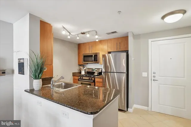 a kitchen with stainless steel appliances granite countertop a refrigerator a sink a stove and island