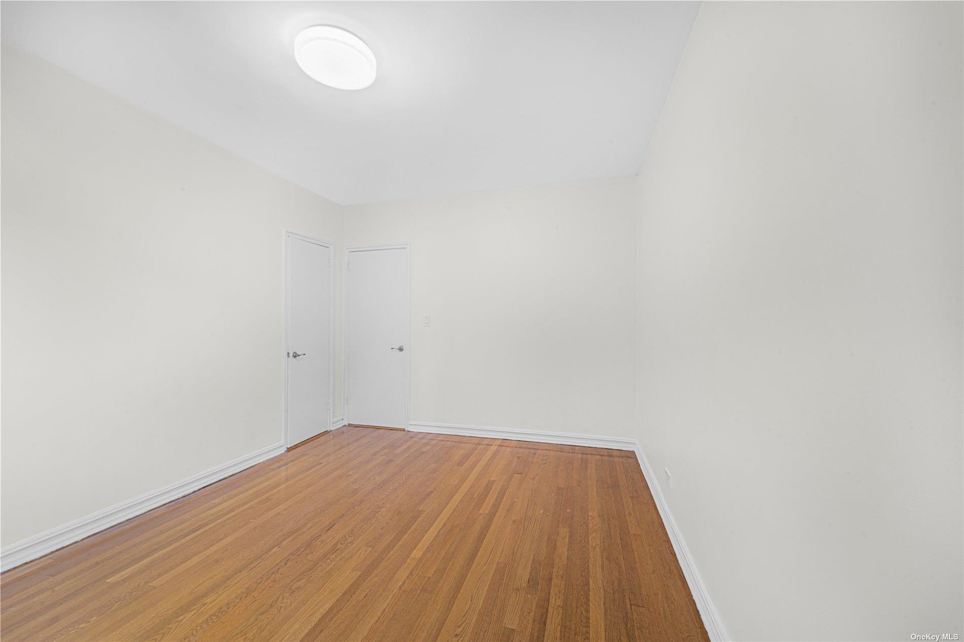 96-11 65th Road, Unit 414 Queens, NY 11374 - Photo 18 of 20 a view of a room with wooden floor and white walls