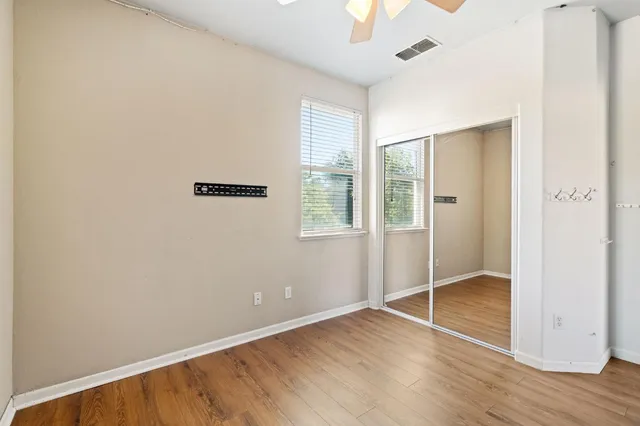 an empty room with wooden floor cabinet and windows