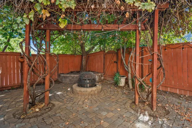 a backyard of a house with table and chairs a barbeque and a large tree