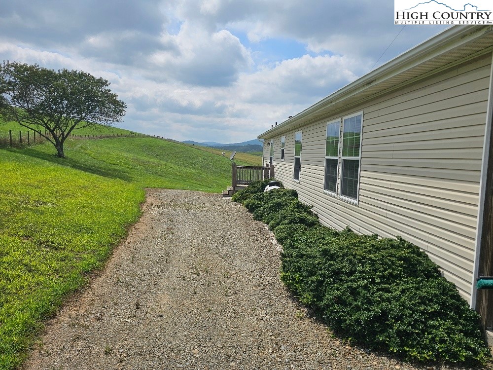 459 Edwards Road Ennice, NC 28623 - Photo 21 of 36 a backyard of a white house with plants and large tree